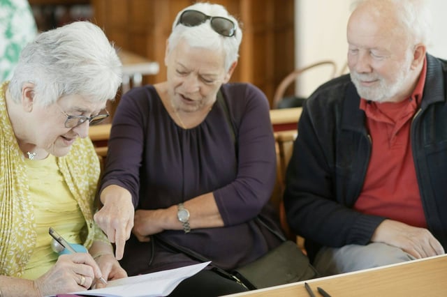 Three people filling in paperwork together at a kitchen table