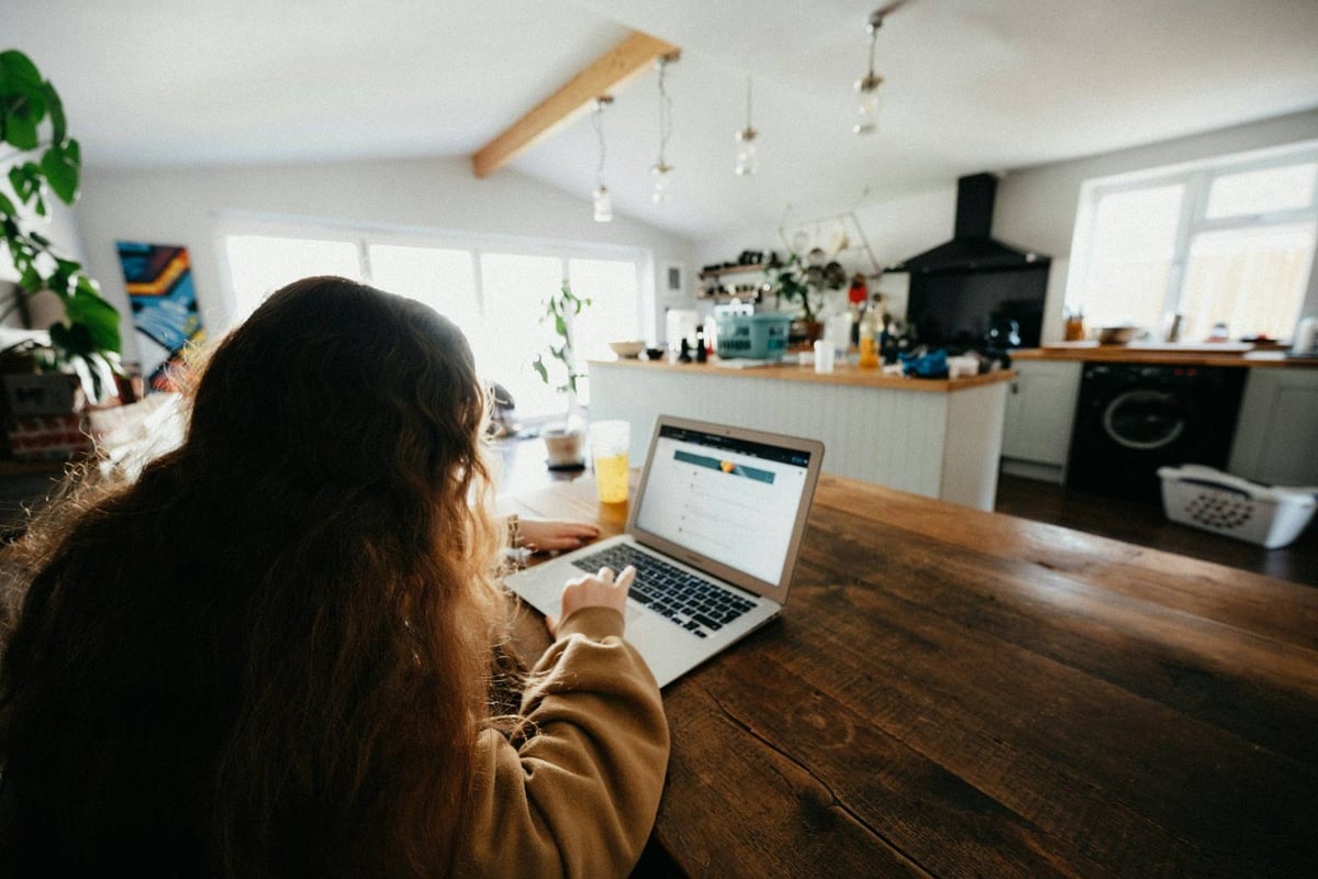 A client at a laptop at a long kitchen table