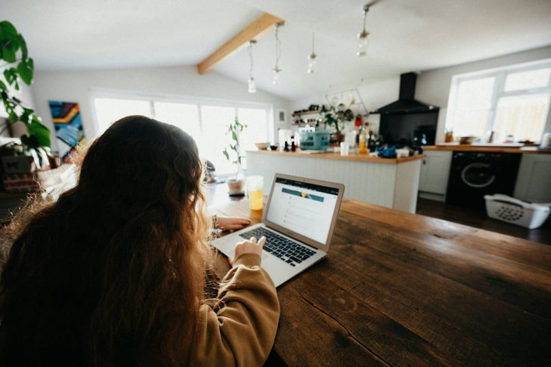 A client at a laptop at a long kitchen table