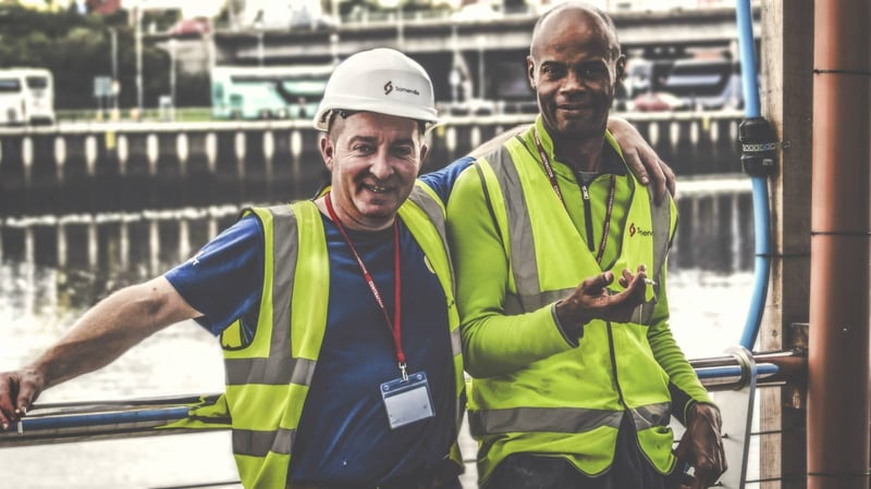 Two site leads in hi-vis vests smiling on a job site
