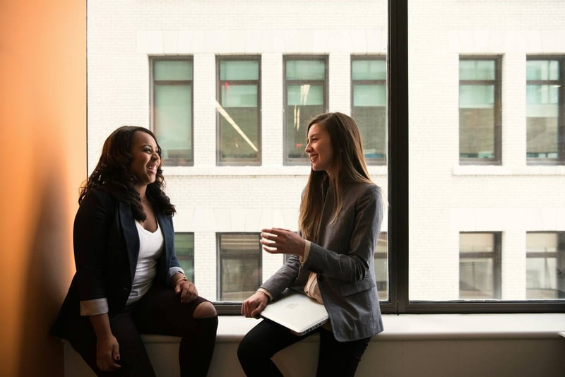 Two colleagues talking by tall windows