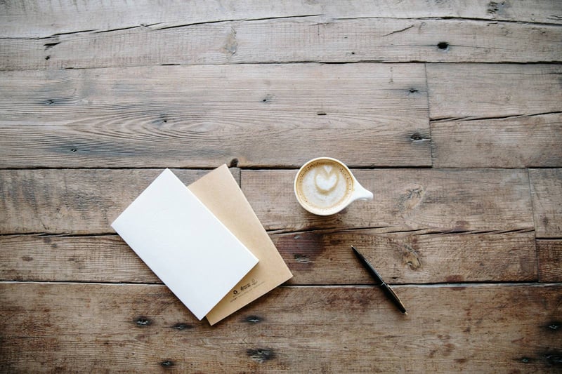 Coffee, an envelope and a pen on a wooden table