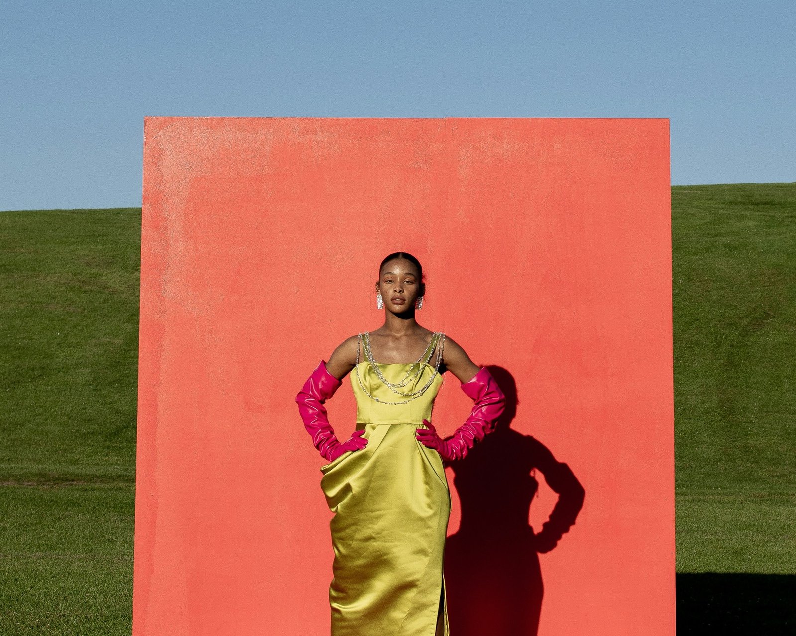 Model in a chartreuse gown against a coral wall